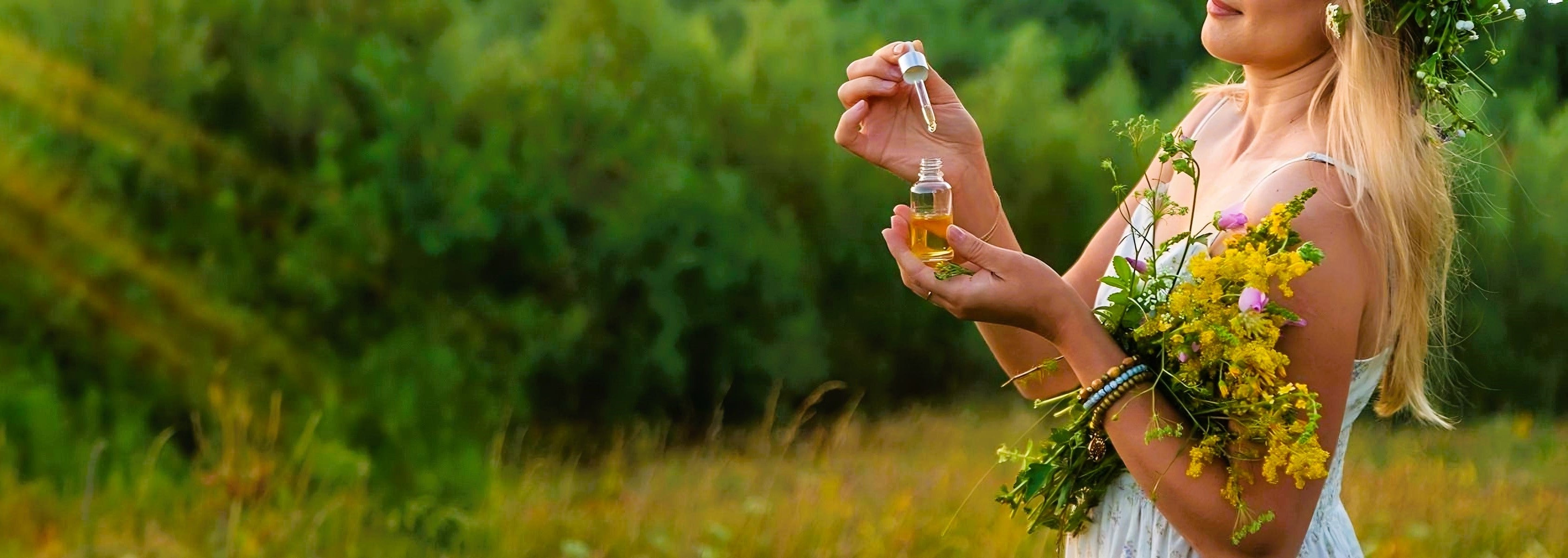 Woman holding a bottle of perfume and a bouquet of flowers in a field